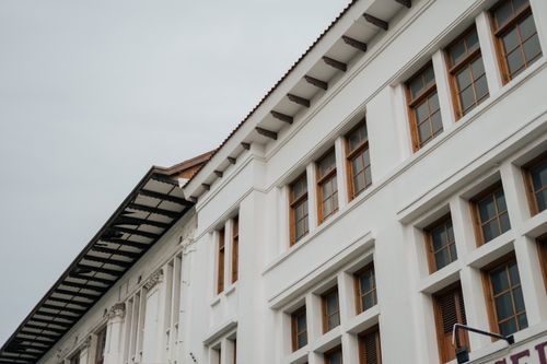Free Low-angle shot of a white building with symmetrical windows against a cloudy sky, showcasing modern architectural design. Stock Photo