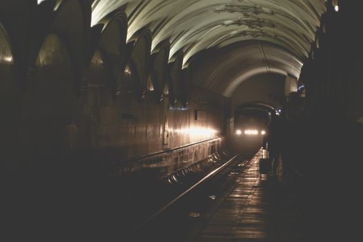 A dramatic view of a metro train emerging in a dimly lit tunnel in Moscow, Russia.