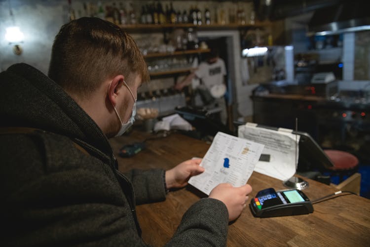 Man In Face Mask Reading Menu At Counter