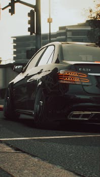 Sleek black car parked at an urban intersection during dusk with modern buildings.