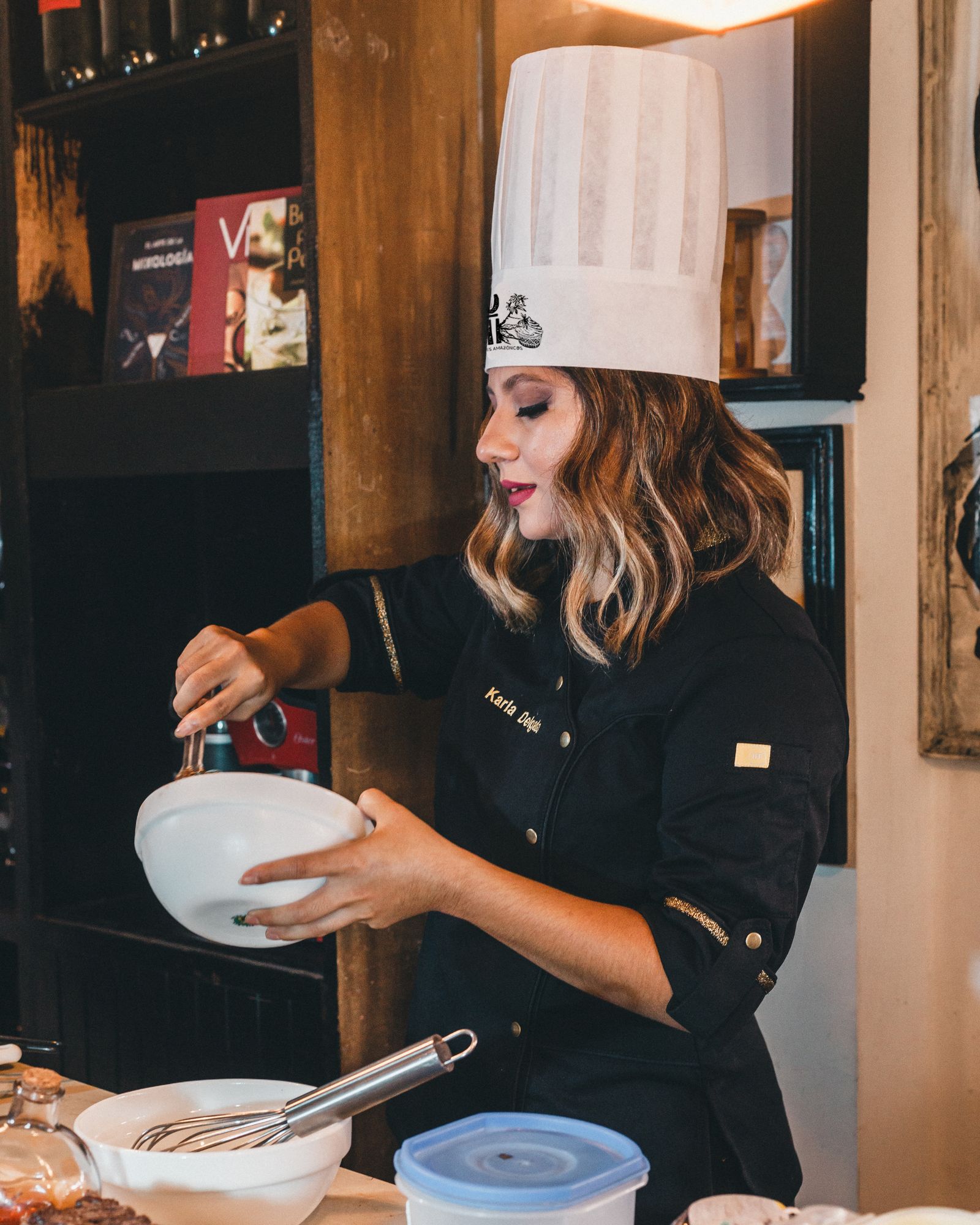 Professional female chef in a hat mixing ingredients in a stylish kitchen