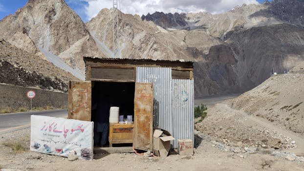 Small roadside shack offering drinks against a stunning mountainous backdrop.