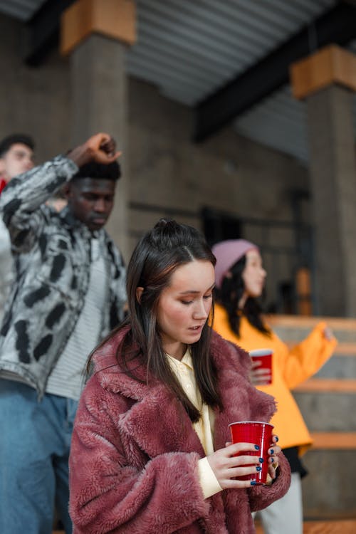 A Woman in Fur Coat Holding a Red Disposable Cup