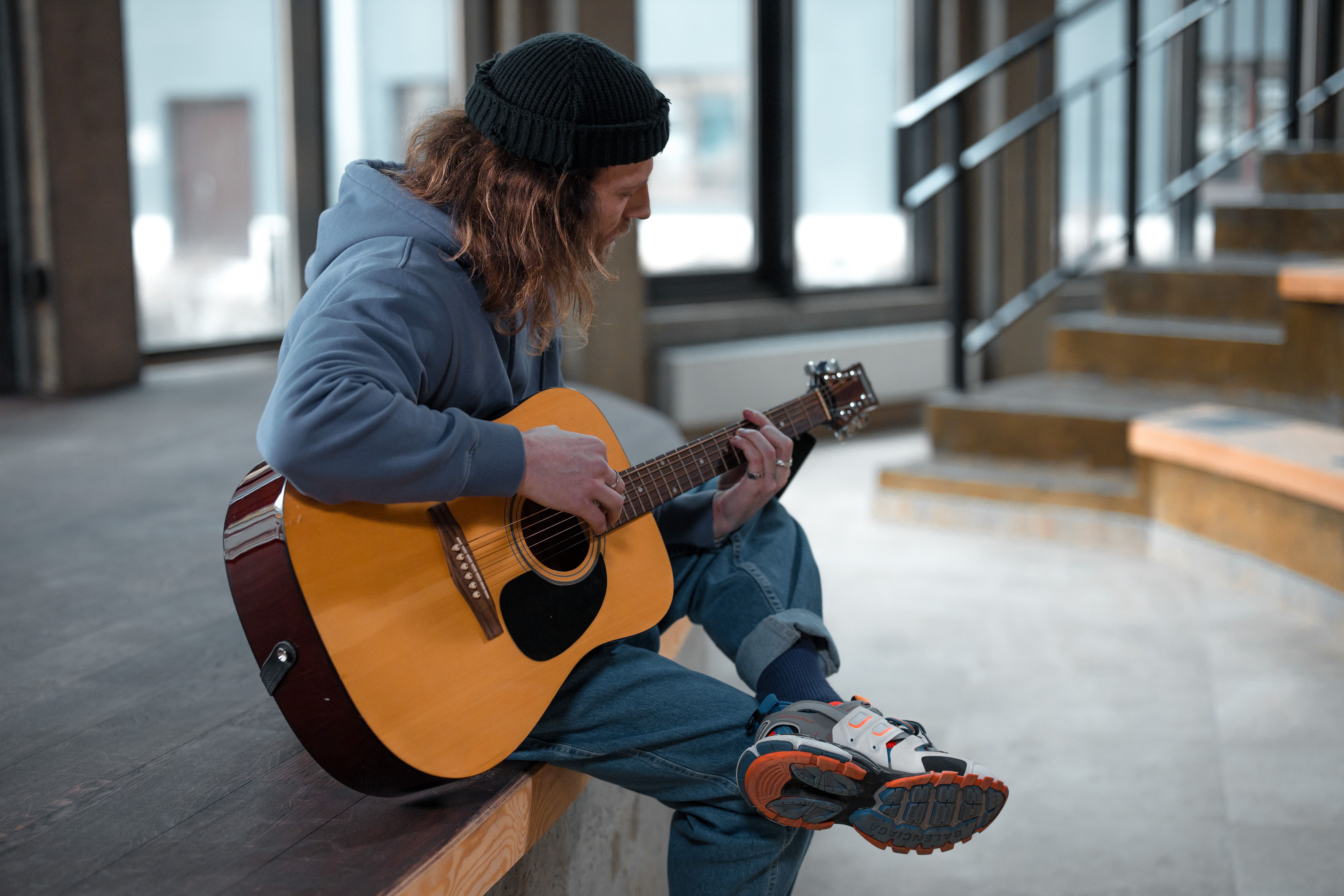 A Man Sitting while Playing Acoustic Guitar · Free Stock Photo