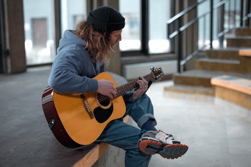 A Man Sitting while Playing Acoustic Guitar
