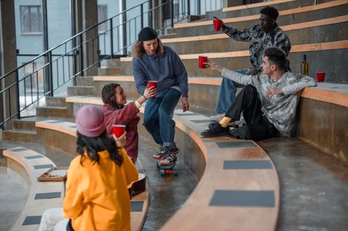 Free Friends enjoying drinks and conversation in an urban amphitheatre setting. Stock Photo
