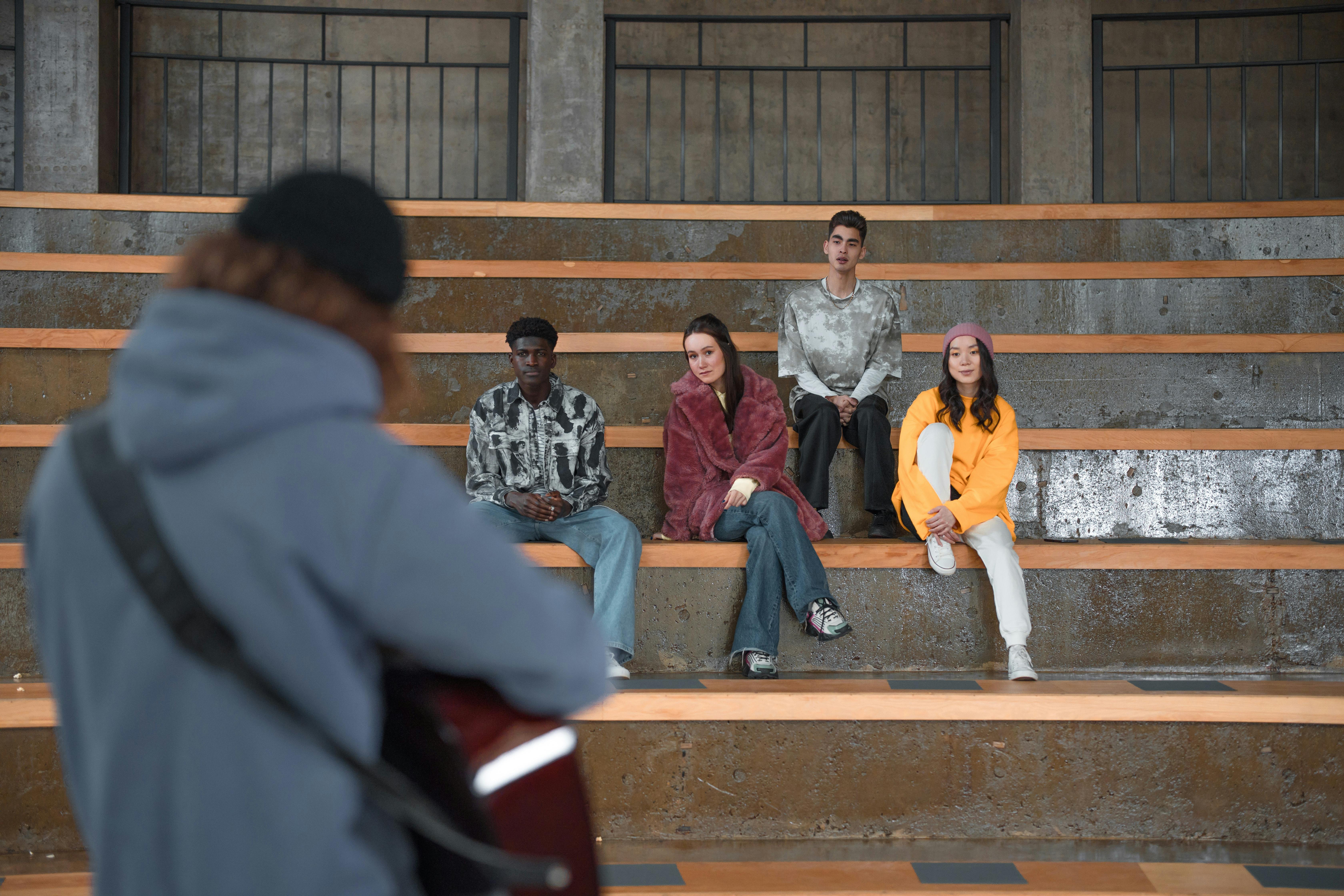 Free A diverse group of young adults attentively watching a guitar performance indoors. Stock Photo