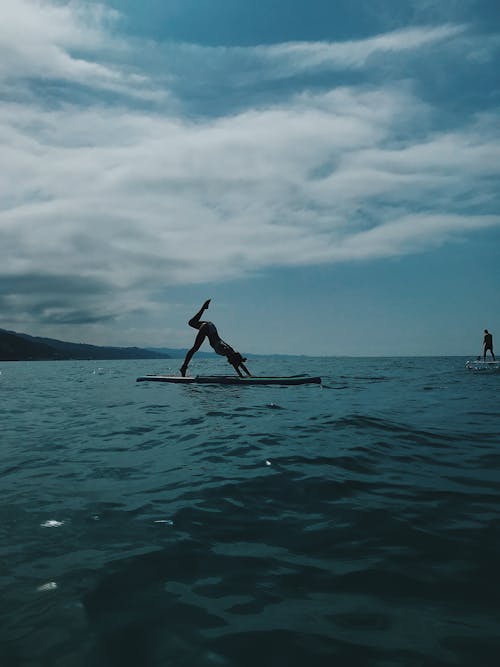 Free A Woman Doing Some Stretches on a Surfboard Stock Photo