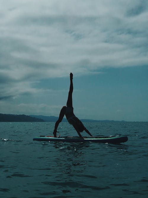 Free Woman in Black Bikini Standing on Surfboard Stock Photo