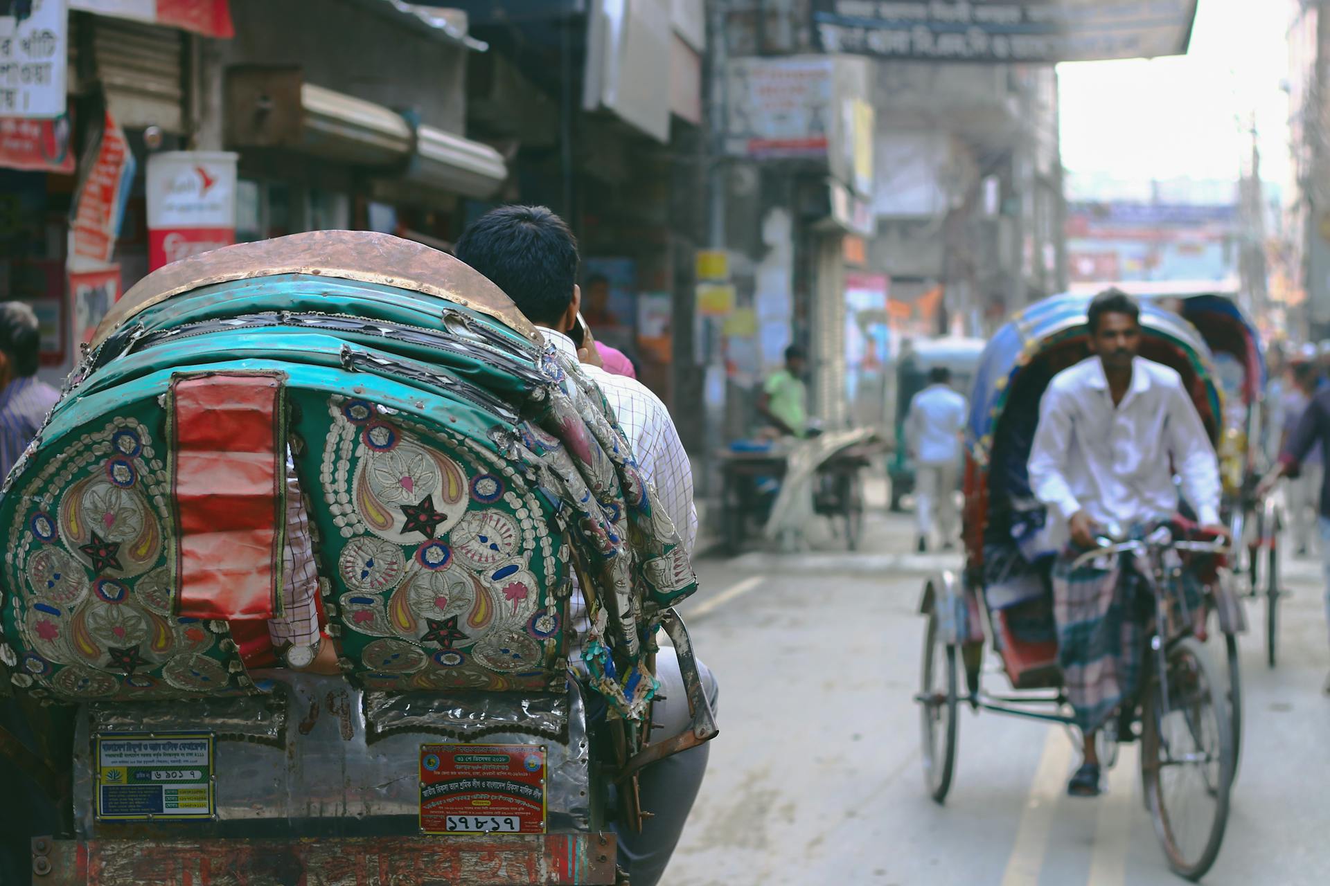 A bustling street scene in Dhaka with rickshaws and local market activity.