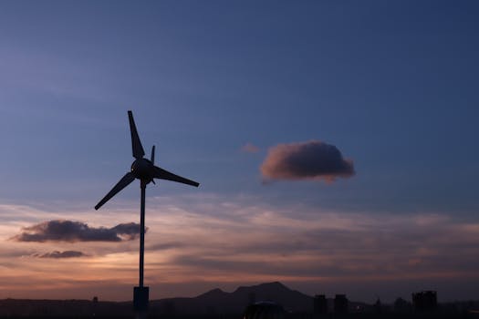 A wind turbine silhouette with a Taipei skyline at sunset, symbolizing renewable energy.