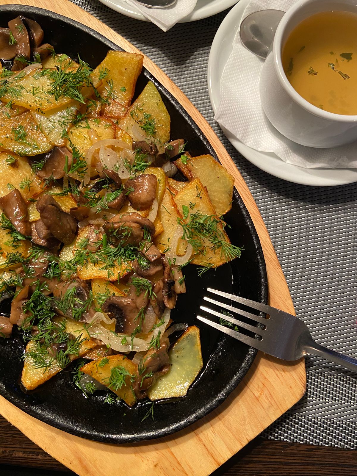 Top view of crispy fried potatoes with mushrooms in a pan, the base for a mashed potato hash topped with a fried egg