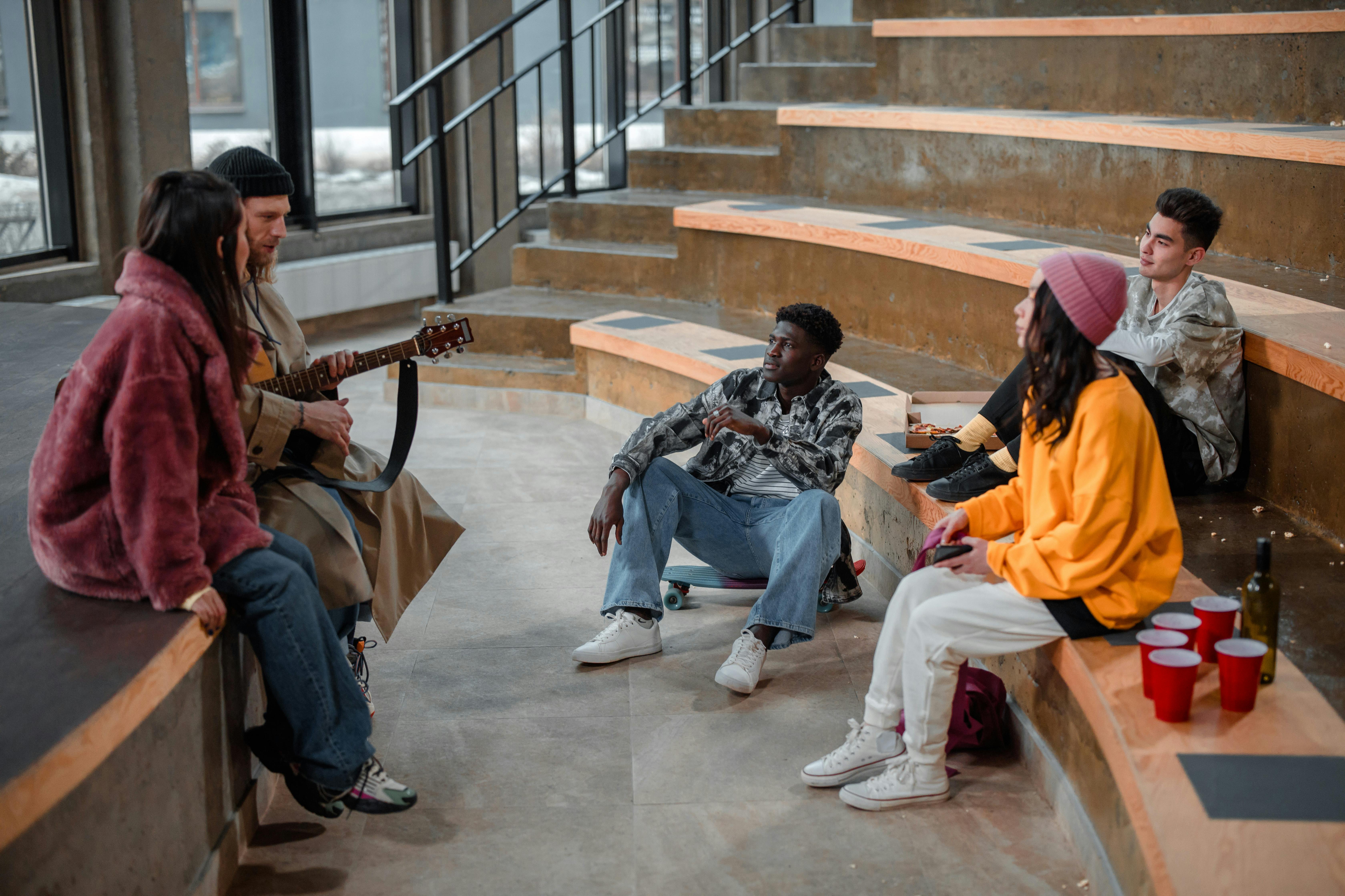 Free Young adults relaxing and conversing in an indoor seating area with a casual vibe. Stock Photo