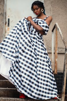 A fashionable woman poses in a plaid dress on an urban staircase, showcasing style and elegance.