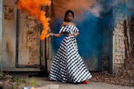 一位时尚女子手持烟雾弹，在户外营造出戏剧性而丰富多彩的场景