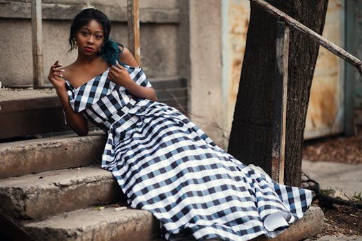 一位穿着格子连衣裙的时尚女子在树旁的台阶上摆姿势