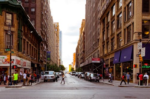 People Walking on Alley Surrounded by High Rise Buildings