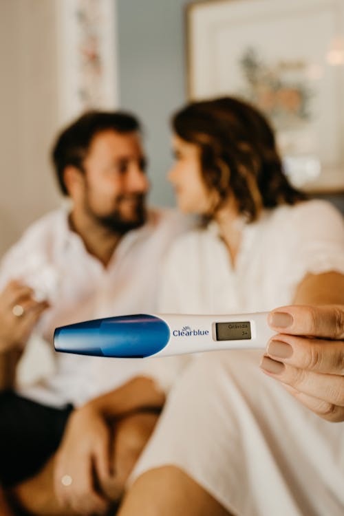 Photo of a Couple and Pregnancy Test in Foreground