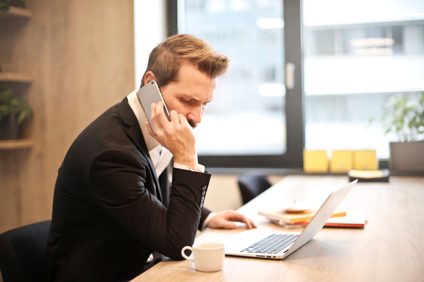 Empresário ao telefone em frente ao notebook