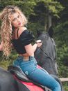 Woman in Black Tank Top and Blue Denim Jeans Sitting on Brown Grass Field With Black
