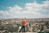 Man with a Red Backpack Standing While near the Rocky View