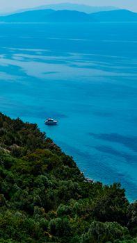 A tranquil aerial view of a boat floating on a serene ocean bay surrounded by lush greenery.