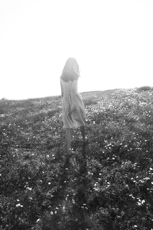 Monochrome Photo of a Woman Going Up a Hill