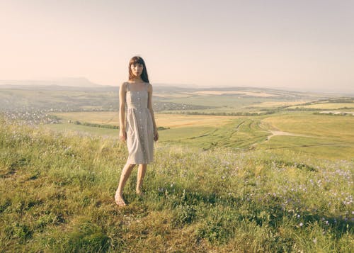 Free Beautiful Woman in a Dress Standing on Grass Field Stock Photo