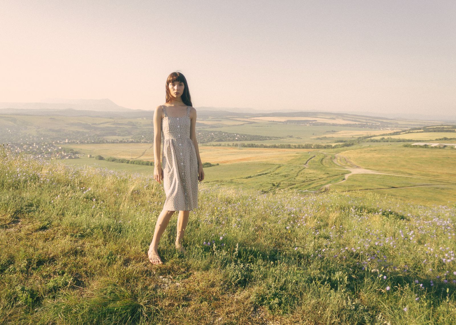 A beautiful woman in a dress standing on a grass field
