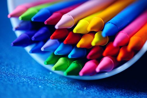 Free A close-up of vibrant colored crayons arranged in a bowl on a blue surface. Stock Photo