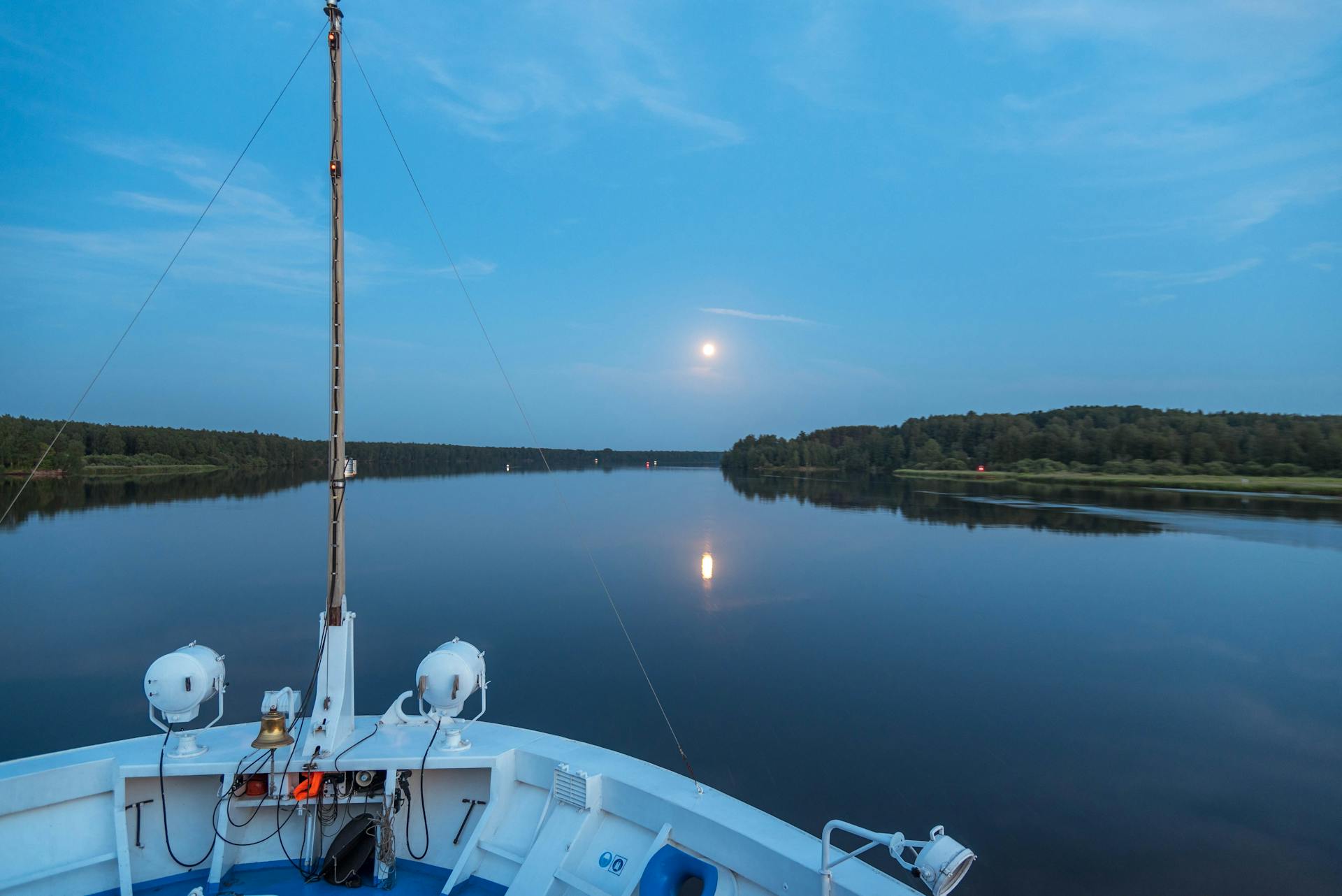 Peaceful cruise on Lake Ladoga, Russia, under full moon with calm reflections on the water.