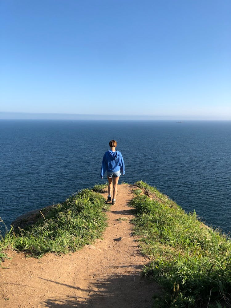 Back View Of A Woman On The Edge Of A Cliff 