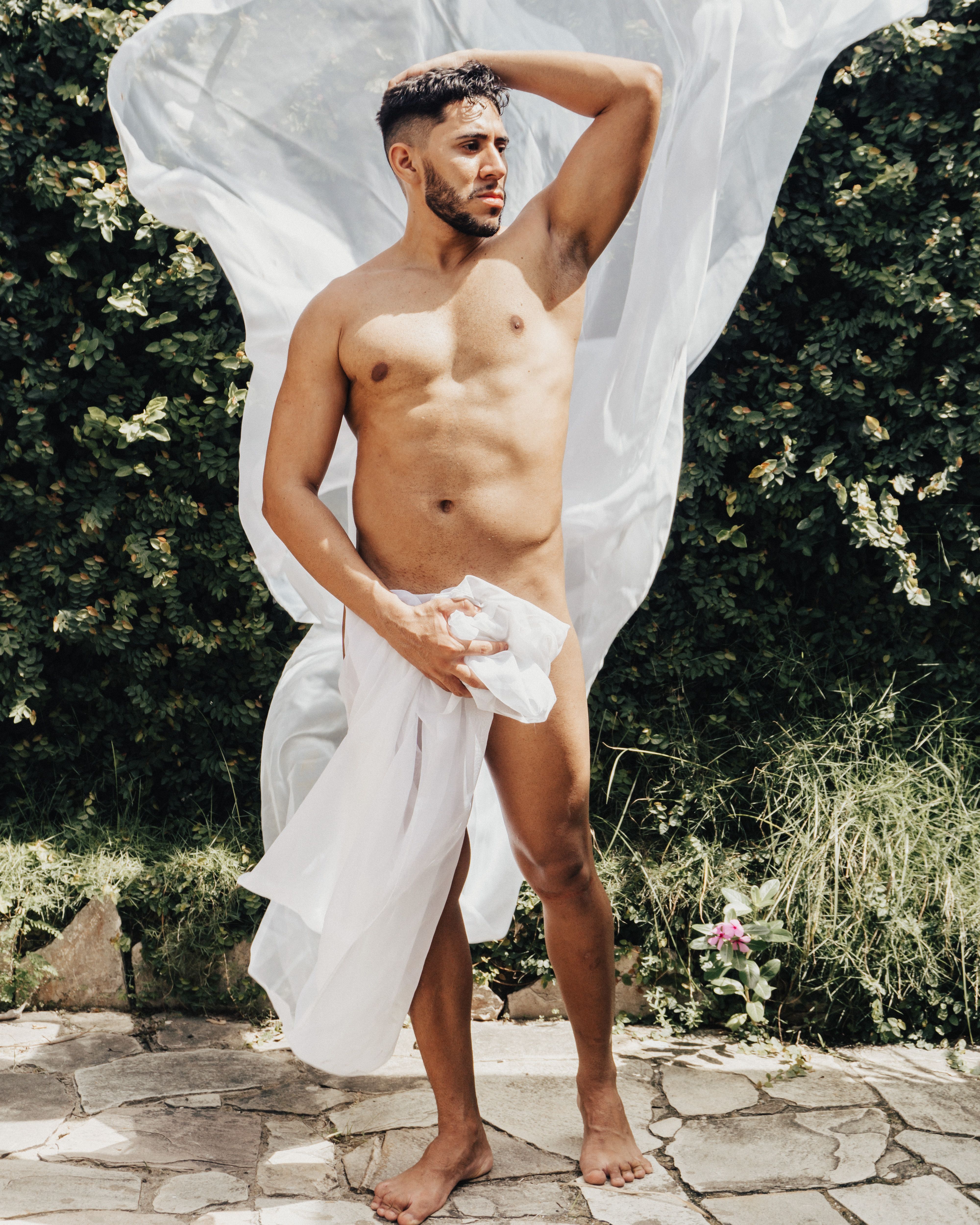 An artistic outdoor photoshoot featuring a male model in a natural setting, posing dynamically.