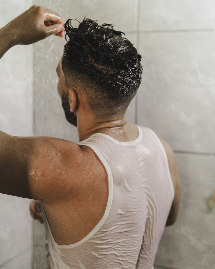 Back View Of A Man In A White Tank Top Taking A Shower