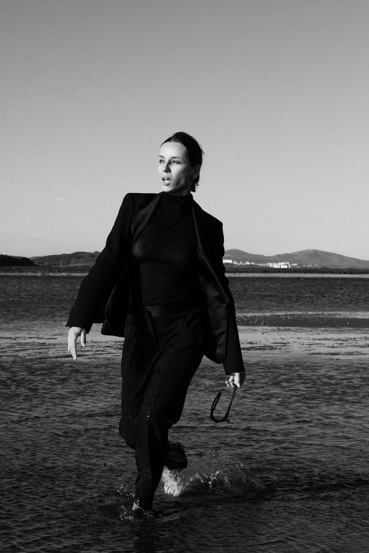 Fashion Model In Black Suit Walking In Water