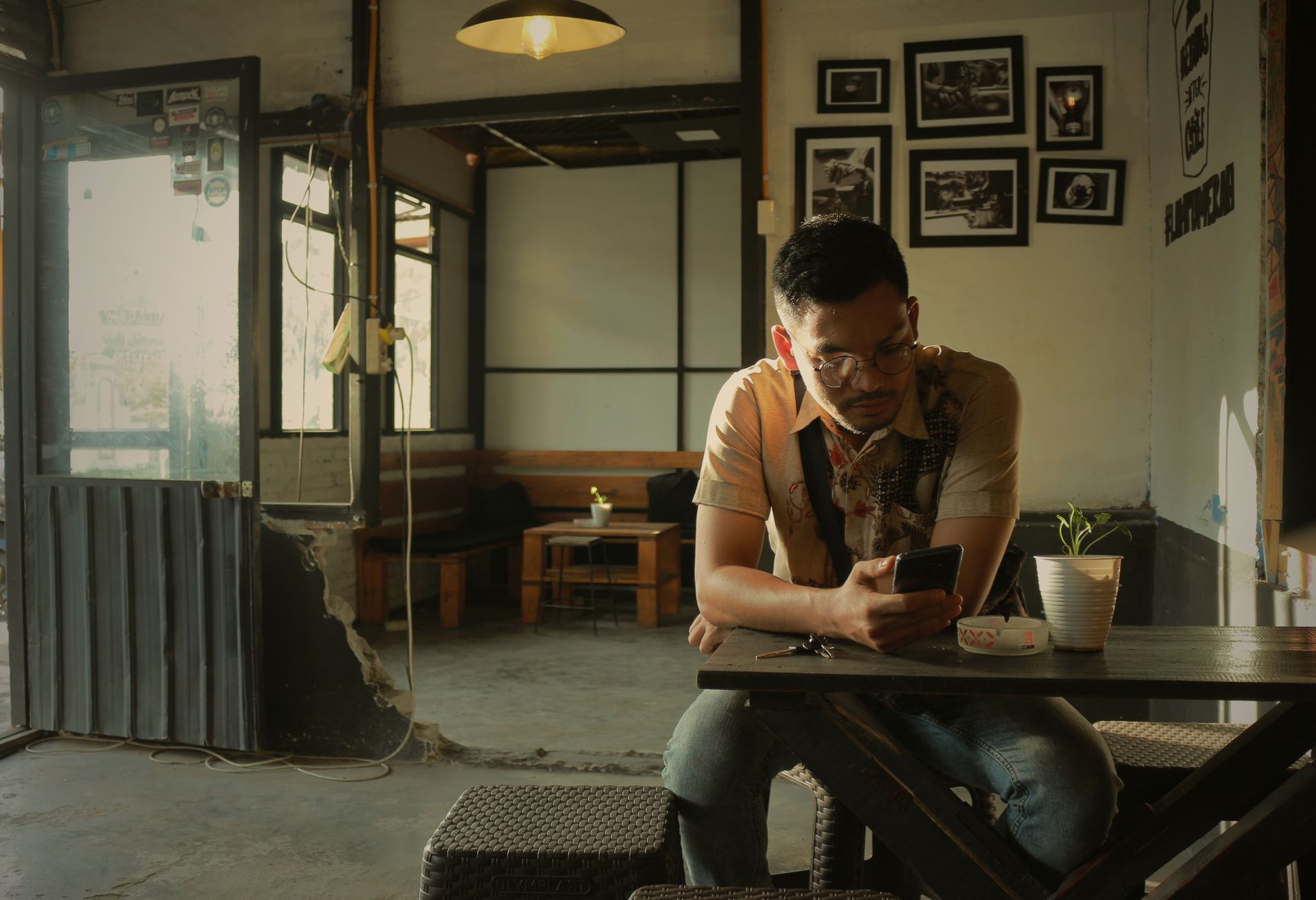 A man in a modern café using his mobile phone while seated at a table. Indoor setting with contemporary decor.