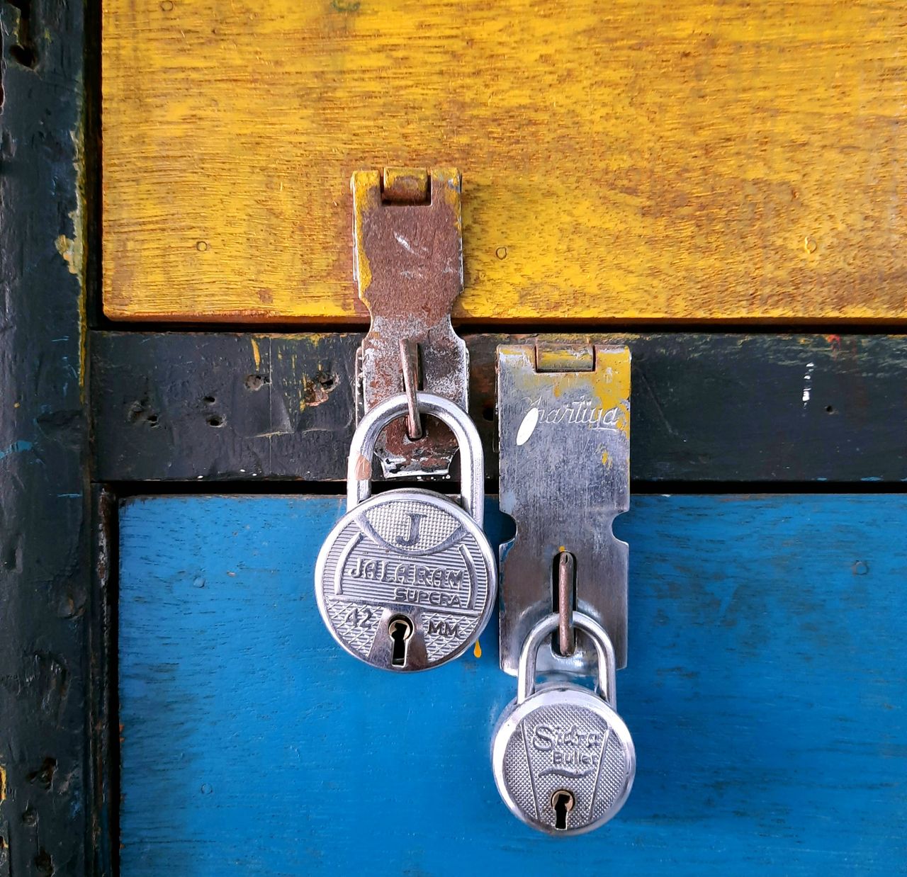 close up of two silver padlocks securing a colorful painted wooden che