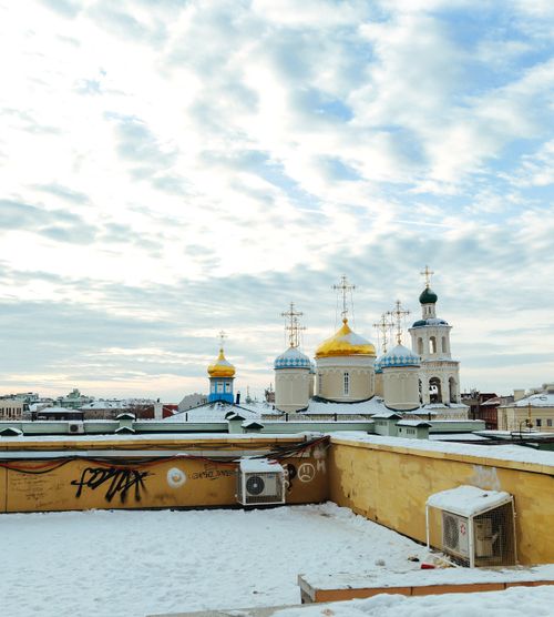 Free Snow-covered rooftop with a view of an Orthodox church's colorful domes against a winter sky. Stock Photo
