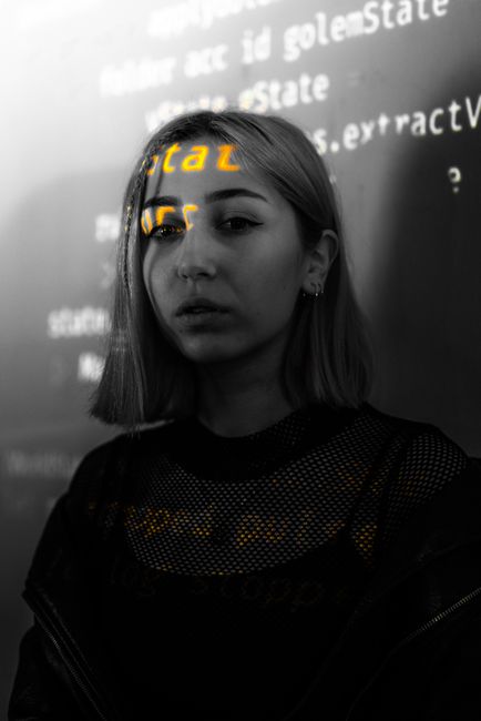 Artistic portrait of a young woman with text projections across her face and background.