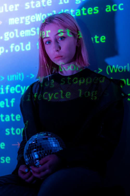 Young Woman Holding a Disco Ball and Being Illuminated by Coding Commands 