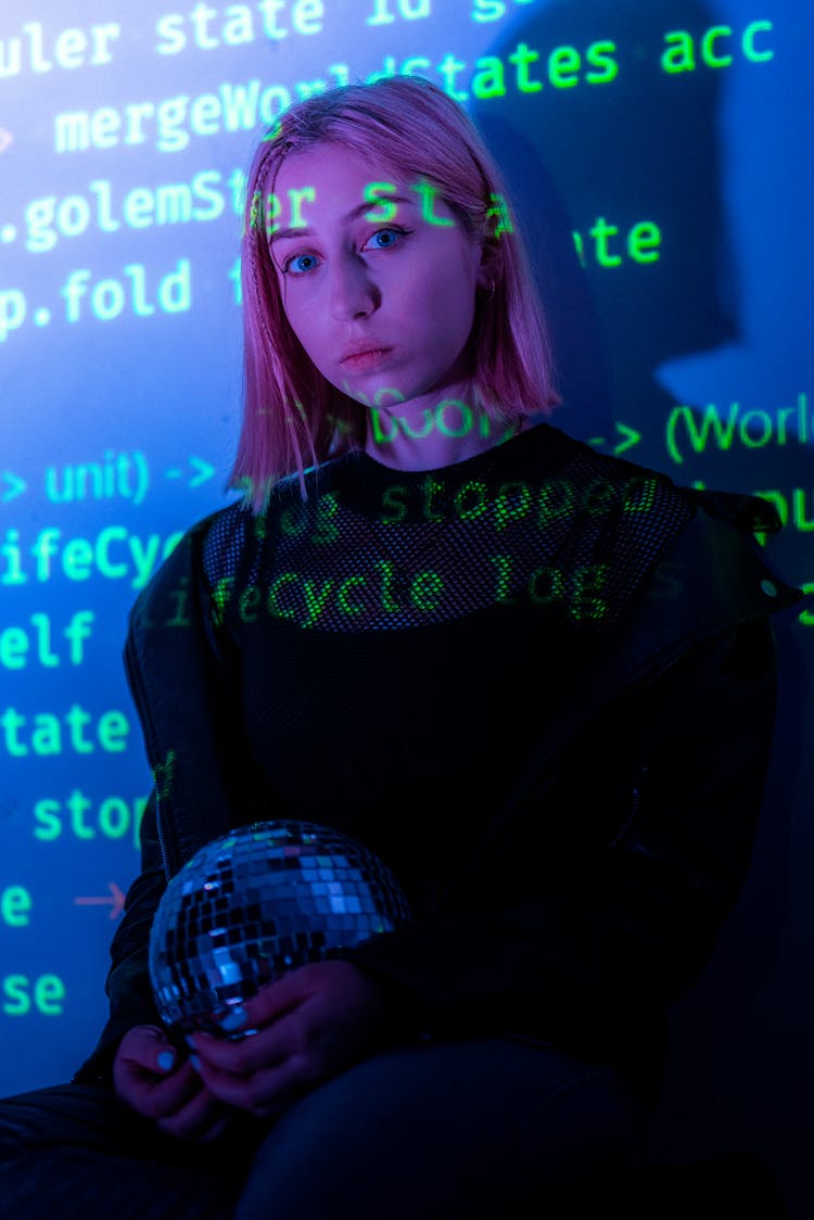 Young Woman Holding A Disco Ball And Being Illuminated By Coding Commands 