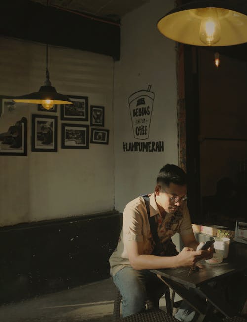 A Man Sitting on a Chair while using a Smartphone