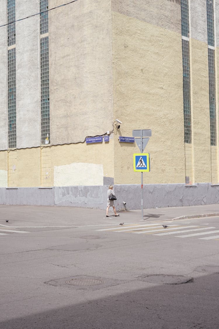 Woman Walking In The Side Walk On The Corner Of The Building