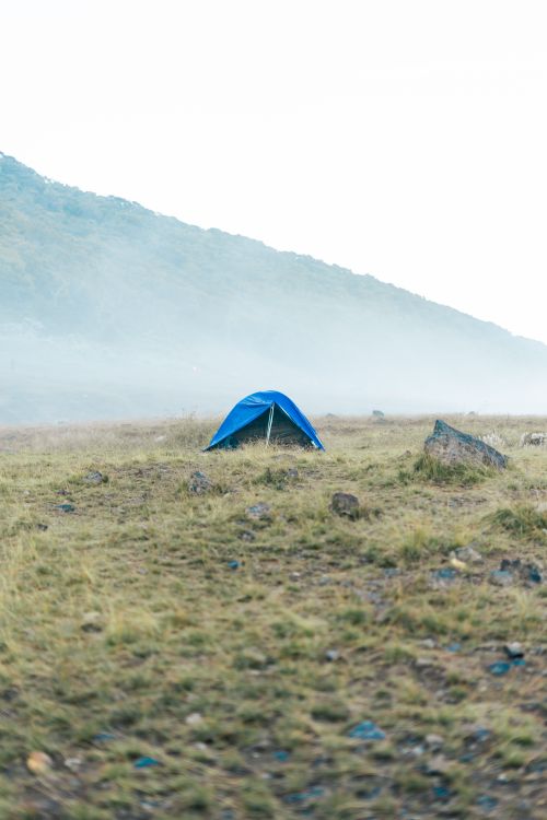 Free A solitary blue tent in a foggy mountain valley, perfect for isolated camping adventures. Stock Photo