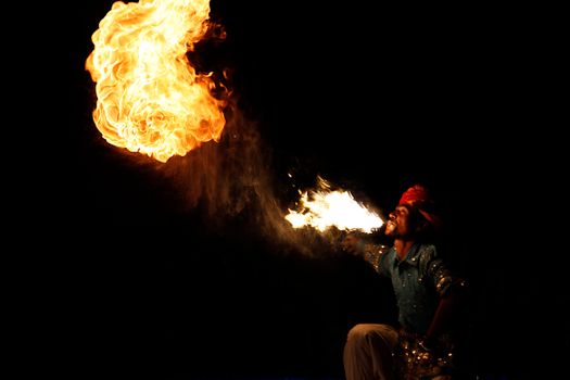 A vibrant spectacle of a performer blowing fire into the dark night, showcasing artistry and skill.