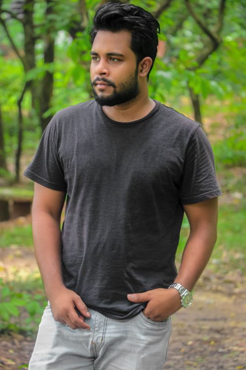 Free Young man wearing casual clothes walking in a lush green outdoor setting. Stock Photo