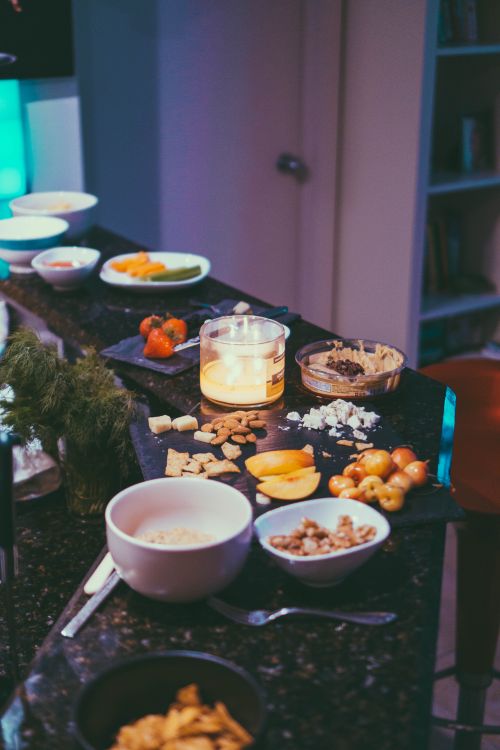 Free Warm, inviting display of assorted snacks, fruits, and nuts on a marble counter with candlelight ambiance. Stock Photo