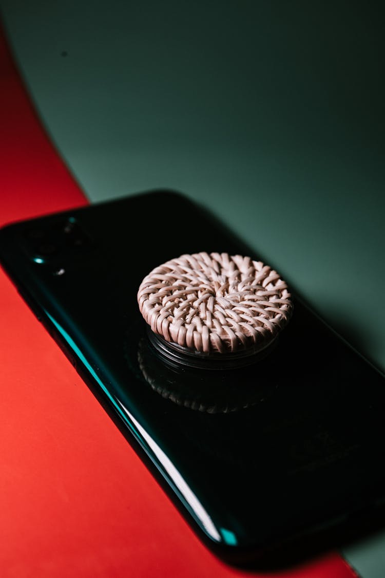 A Black Phone With Rattan Phone Grip At The Back