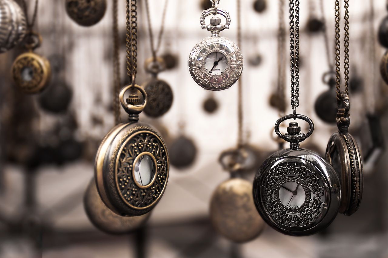 close up of antique pocket watches with intricate designs hanging in a