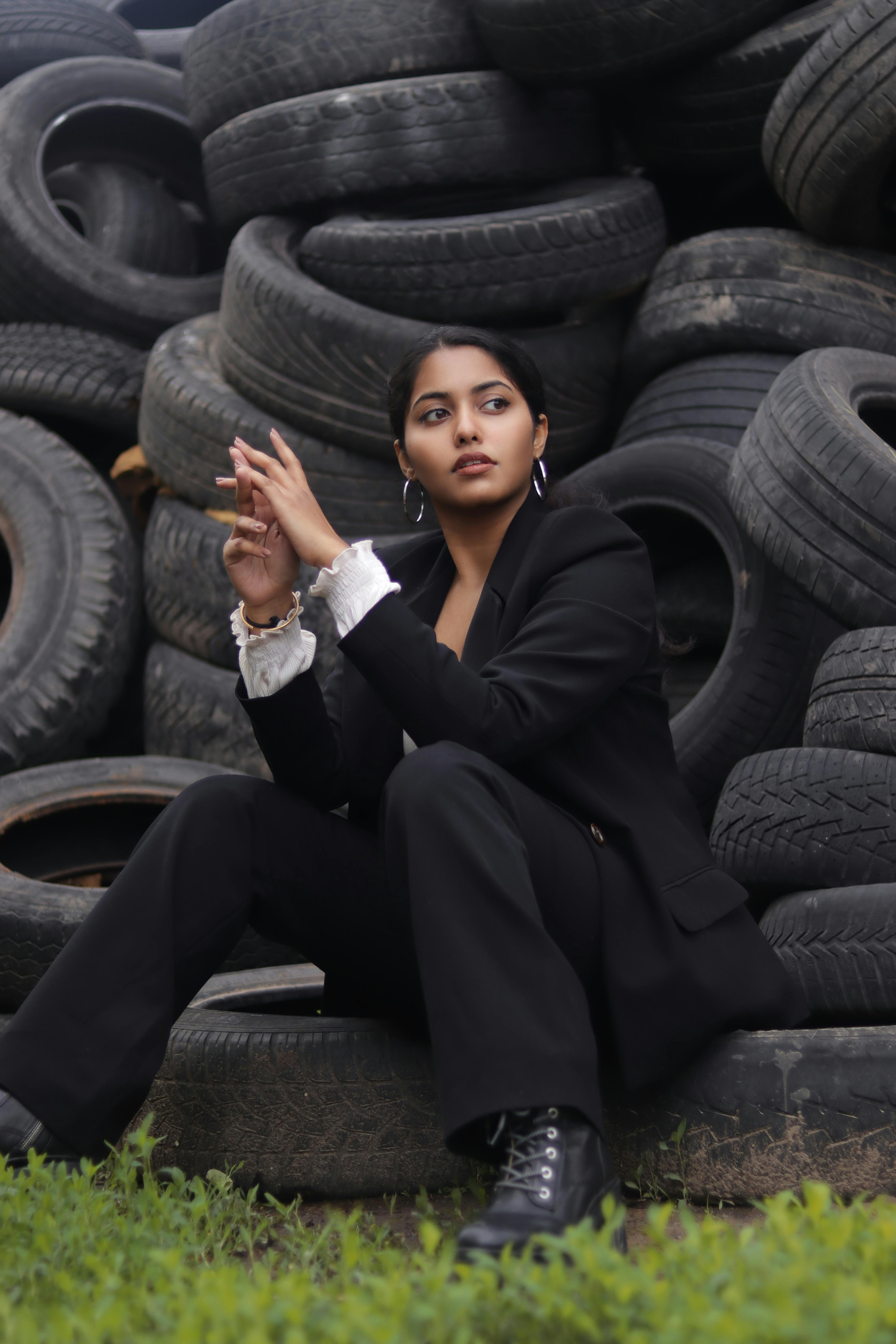 a woman in black blazer and pants sitting on a black tires